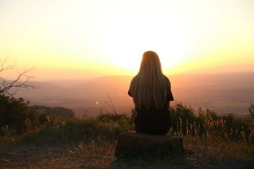 A picture shows a girl facing the sunset.