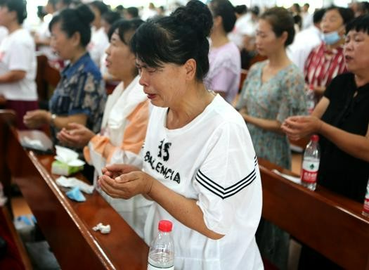 A female believer prayed with tears holding the holy bread during a joint baptism service in Shengli Church, Tai'an County, Anshan, Liaoning, on August 13, 2022.