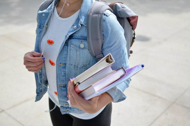 A picture shows a young woman holding some books.