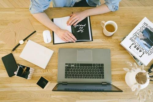 A picture shows a person beside a table with a book and a notebook.