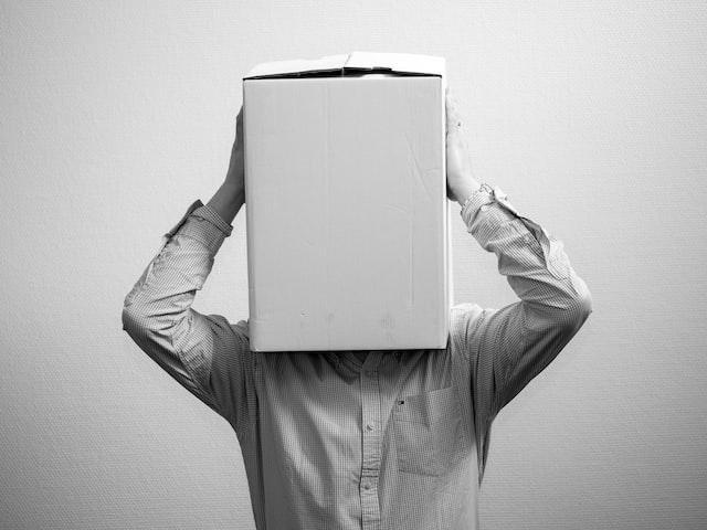 A picture shows a person covering his head with a cardboard box.