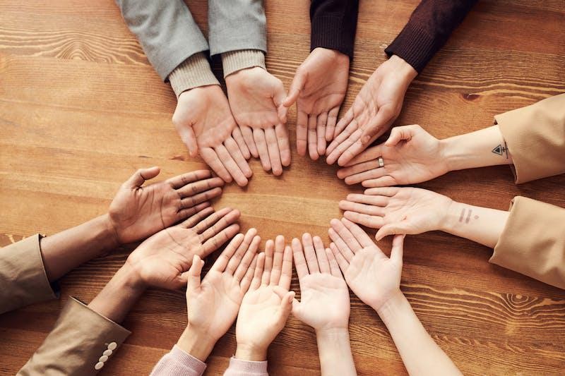 A picture showing five persons circling hands together.
