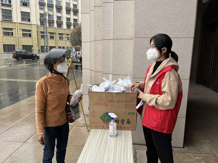 A female member of Beimen Church in Zhangzhou, Fujian, sent out a packet of three  masks and a COVID-19 rapid antigen test kit to a passer-by at the gate of the church  on January 10, 2023.
