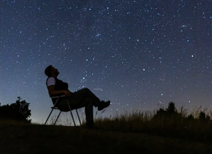A picture of a man sitting in a chair at night