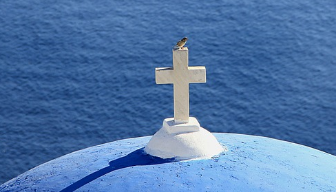 A picture of a cross over the sea with a bird on it