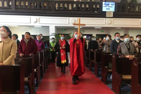 The officiant with a cross high, preacher, and choir members entered the main building of St. John's Church in Suzhou, Jiangsu, on April 2, 2023.