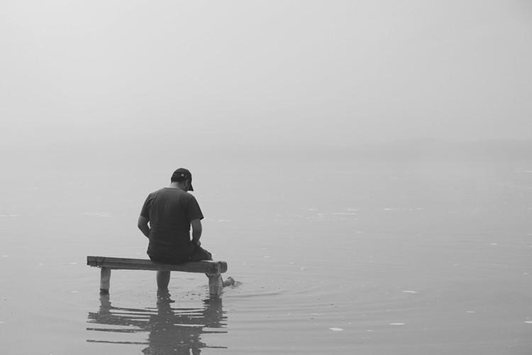 A picture of a man sitting on a river