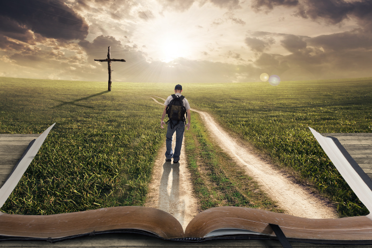 A man is walking towards a cross ahead on the greenfield of a huge Bible.